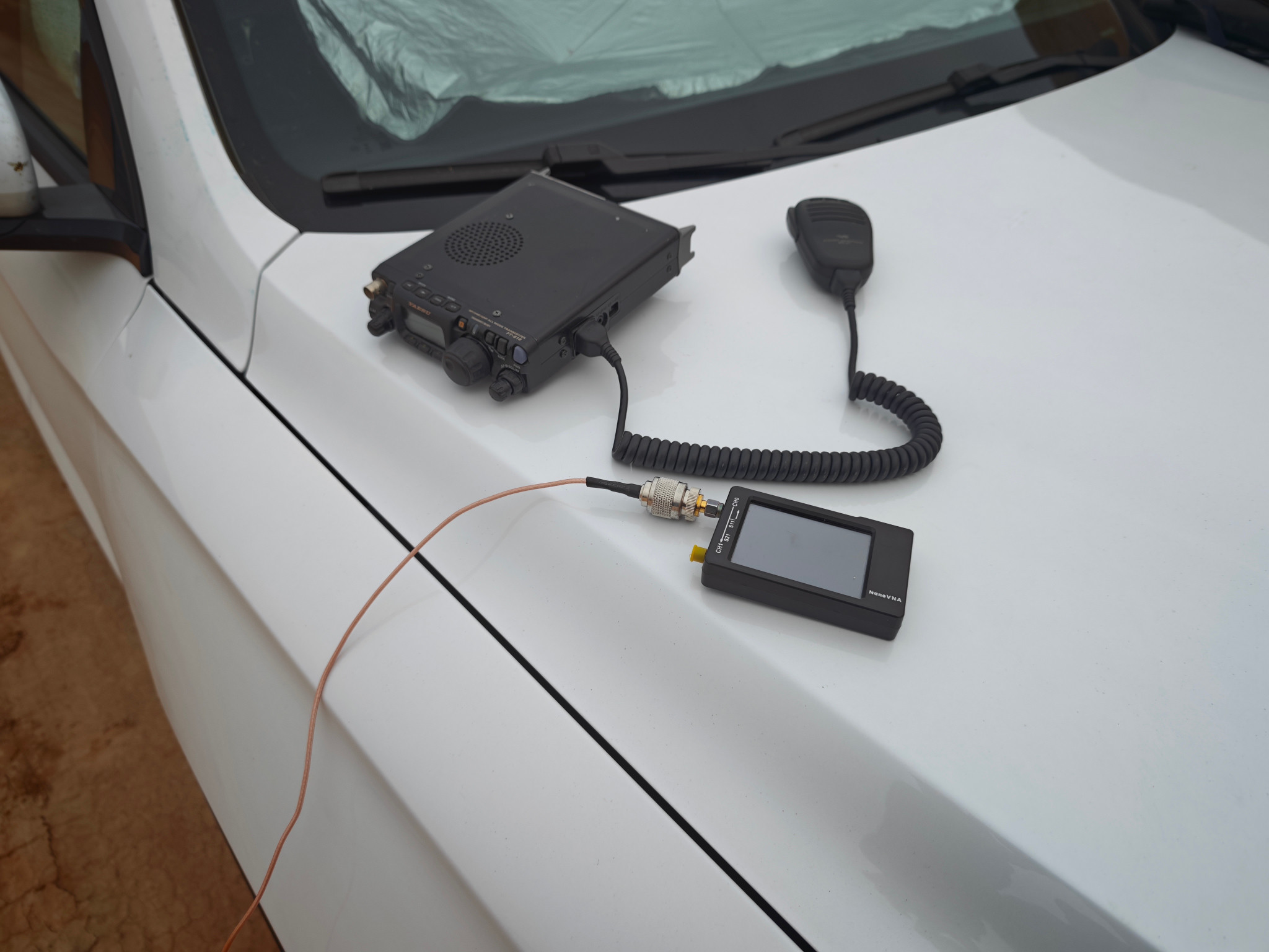 The radio, hand microphone, and measuring equipment on the car hood.